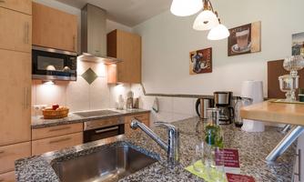 Modern kitchen with wooden cabinets and granite countertops. It includes various kitchen appliances and has a bright, inviting atmosphere.