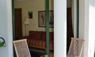 A cozy entrance area with two wooden chairs and a flower pot. In the background, there is a living room with a sofa.