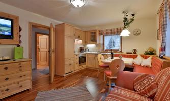 A cozy holiday apartment with a modern kitchen and an inviting living area. Bright wooden paneling and loving decoration create a warm atmosphere.