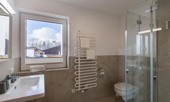 A modern bathroom with a shower and a large window. The bright walls and neutral colors create an inviting atmosphere.