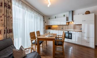 A modern kitchen with a dining table and four chairs. Large windows provide plenty of daylight and create an inviting atmosphere.