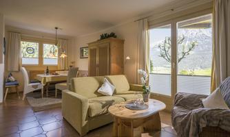 A bright living room with a comfortable sofa and a table. Large windows offer a beautiful view of the mountains.