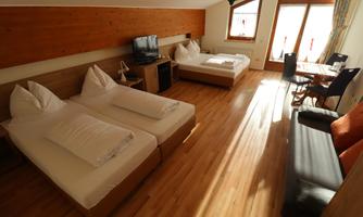 A cozy room with two single beds and wooden flooring. Large windows provide plenty of light and an inviting atmosphere.