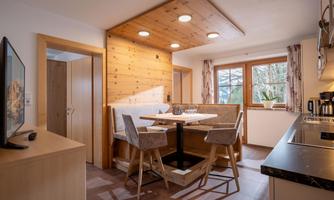 A cozy kitchen with a dining area and wood paneling. Large windows provide plenty of light and a view outside.