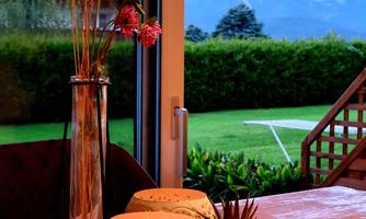 A cozy table with decorative vases and plants. In the background, the mountains and a green landscape are visible.