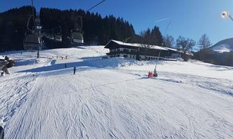 A beautiful winter landscape with snow-covered slopes and a ski lift. In the background, there is a cozy ski lodge.