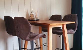A modern dining area with a wooden table and four high chairs. A deer antler hangs on the wall, giving the room a rustic touch.