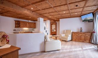 A cozy living kitchen with a wooden ceiling and modern furniture. A television and a bright atmosphere give the room an inviting mood.