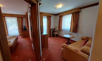 A cozy furnished room with a sofa and a table. Large windows provide plenty of natural light and an inviting atmosphere.