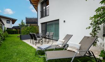A modern garden area with two loungers and a dining table. The building is bright and invites relaxation.