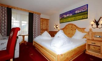 A cozy room with a large wooden bed and white pillows. The room is decorated in a rustic style and has a view of the mountains.