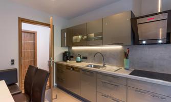 A modern kitchen with shiny gray cabinets and an elegant sink. The space is well-lit and has a friendly atmosphere.