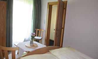 A bright room with a bed, a table, and chairs. The window lets in a lot of light and creates an inviting atmosphere.