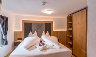 A modern bedroom with a large bed and cozy lighting. Wooden cabinets are along the wall, and there are decorative pillows on the bed.