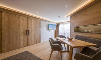 A modern living space with wood paneling and a cozy table. A television is hung on the wall, providing entertainment.