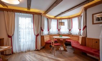 A cozy dining area with a wooden bench and table. The windows let in plenty of light and the decor is stylish and inviting.