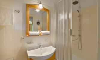 A modern bathroom with a sink and a mirror. There is a shower and towels are laid out.
