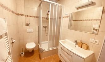 A modern bathroom with a shower and a sink. The tiles are bright, and the room feels clean and inviting.