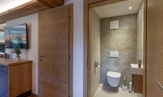A modern bathroom with neutral colors and contemporary furnishings. The door leads to a stylish toilet and a sink.