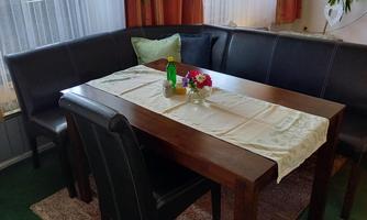A cozy dining area with a wooden round table and black chairs. A small flower vase is on the table.