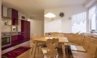 A bright kitchen with a spacious wooden dining area. The furniture is modern and the walls are in soft colors.