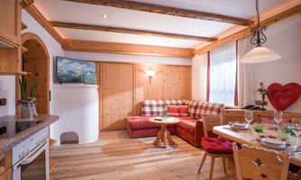 A cozy living room with wooden paneling and a comfortable sofa. There is a dining table, a kitchen, and a warm atmosphere.