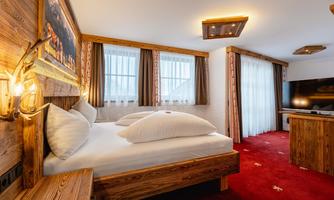 A cozy room with a double bed and a modern television. The wood style and warm colors create an inviting atmosphere.