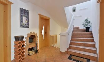 A bright hallway with a staircase and a modern fireplace. A picture hangs on the wall and a plant is standing in the corner.