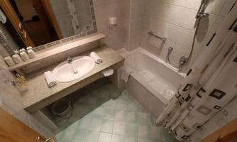 A clean bathroom with a bathtub and a sink. The walls are tiled and there are towels on the table.