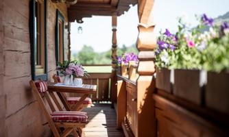 A cozy balcony with a small table and flowers. The wood paneling and the view create an inviting atmosphere.