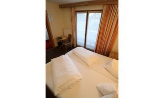 A cozy double room with two beds and soft pillows. Large windows let in plenty of light and offer a view of the scenery.