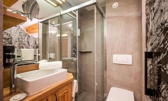 A modern bathroom with a shower and an elegant wooden vanity. The walls are stylishly designed and the lighting is pleasant.