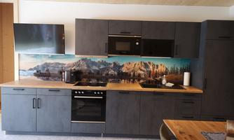 A modern kitchen with dark cabinets and a wooden countertop. The background image shows a mountainous landscape.