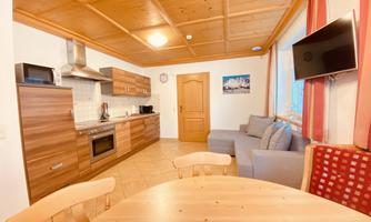 A cozy kitchen with wooden furniture and modern appliances. The dining area is bright and welcoming, with a table and comfortable chairs.