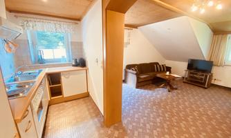 A cozy holiday apartment with an open kitchen and a living area. The room is brightly and warmly designed.