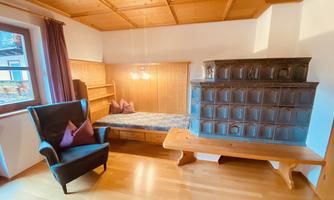 A cozy room with a comfortable armchair and a wooden stove. The walls are made of wood, and there is a windowsill for relaxing.