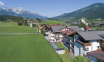 A picturesque landscape with green meadows and mountains in the background. The image shows a tranquil village with traditional buildings.
