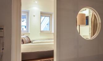 A modern room with a view of a bright bedroom. The room is friendly and well-lit, with a cozy bed and large windows.