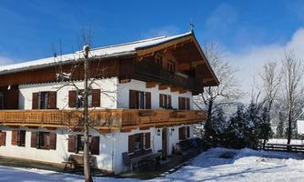 A cozy house in the snow with a wooden balcony. The clear blue sky provides a beautiful winter landscape.