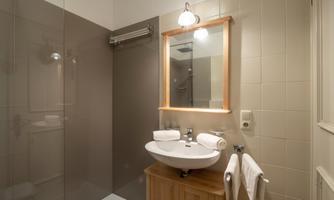 A modern bathroom with a shower and a sink. There is a wooden cabinet and a mirror on the wall.