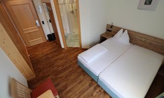 A simple room with a double bed and wooden furniture. The room has a modern look and a private bathroom area.