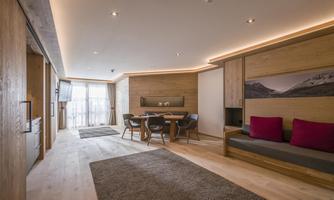 A modern living environment with wood paneling and cozy furniture. The room features a dining area and access to a balcony.
