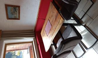 A cozy dining area with a wooden table and gray chairs. The red benches and the window create an inviting atmosphere.