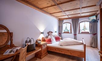 A cozy bedroom with wooden furniture and a large window. The room has a warm, inviting ambiance.