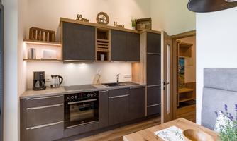A modern kitchen with dark cabinets and clean lines. A coffee machine and decorative elements are on the countertop.