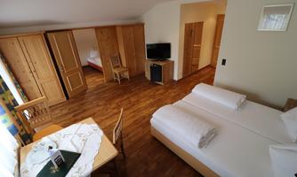 A room with two single beds and a table. The furnishings are made of wood, with a television and plenty of space.