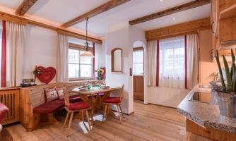 A cozy kitchen with wooden furniture and a round table. Red chairs and an inviting atmosphere create a warm ambiance.