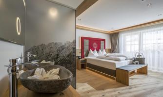 A modern room with a comfortable bed and large windows. The decor combines wood and elegant design elements.