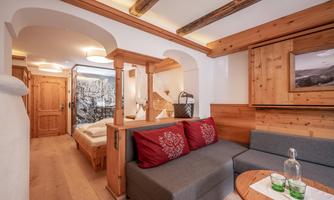 A cozy living room with wooden furniture and a sofa. The walls are tastefully decorated, and there is a beautiful view of nature.