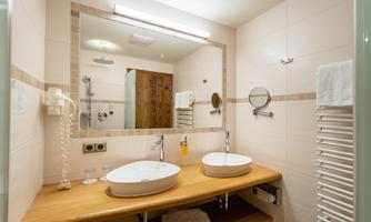 A modern bathroom with two sinks and a large mirror. The walls are light and the furnishings are functional.